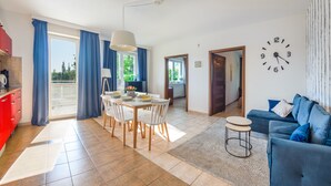Een moderne woonkamer met een eethoek, een bank, een klok en uitzicht op de omgeving.