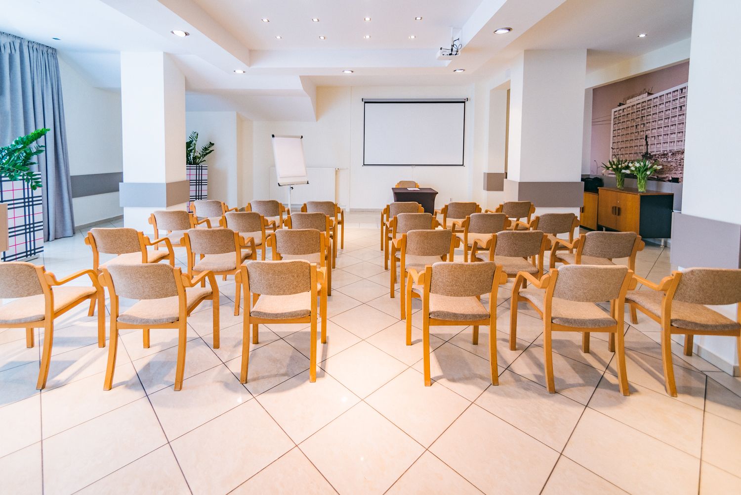 A conference room with rows of chairs, a projector screen, and a whiteboard.