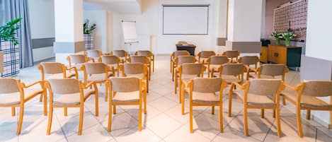 A conference room with rows of chairs, a projector screen, and a whiteboard.