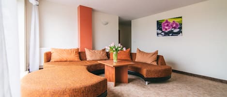 Una sala de estar moderna con un sofá seccional curvo, una mesa de centro de madera y un jarrón de flores.