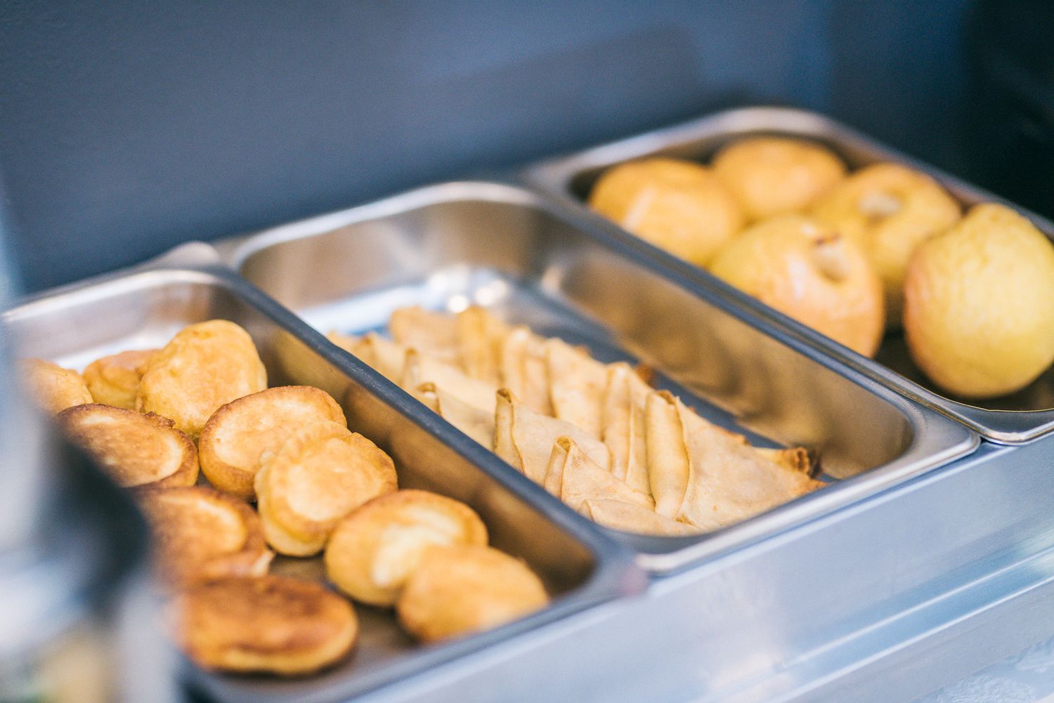 A buffet with various food items including fried pastries and sliced apples.