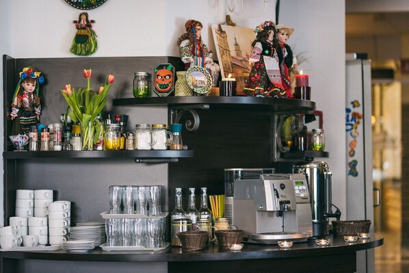 A kitchen counter with a coffee machine, shelves with kitchenware, decorative items, and a wall with cultural decorations. - Hotel Forum (Rzeszów)