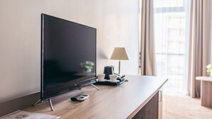 Habitación de hotel moderna con una televisión de pantalla plana sobre un escritorio de madera, una lámpara y un control remoto.