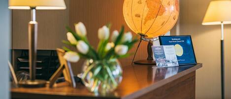 A reception desk with a globe, a framed certificate, and a vase of tulips.