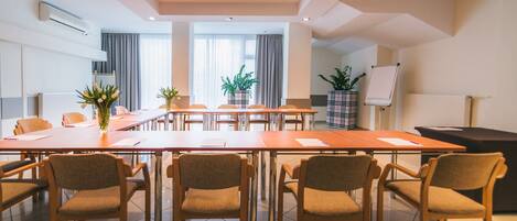 Une salle de conférence avec une longue table, des chaises et un tableau blanc.