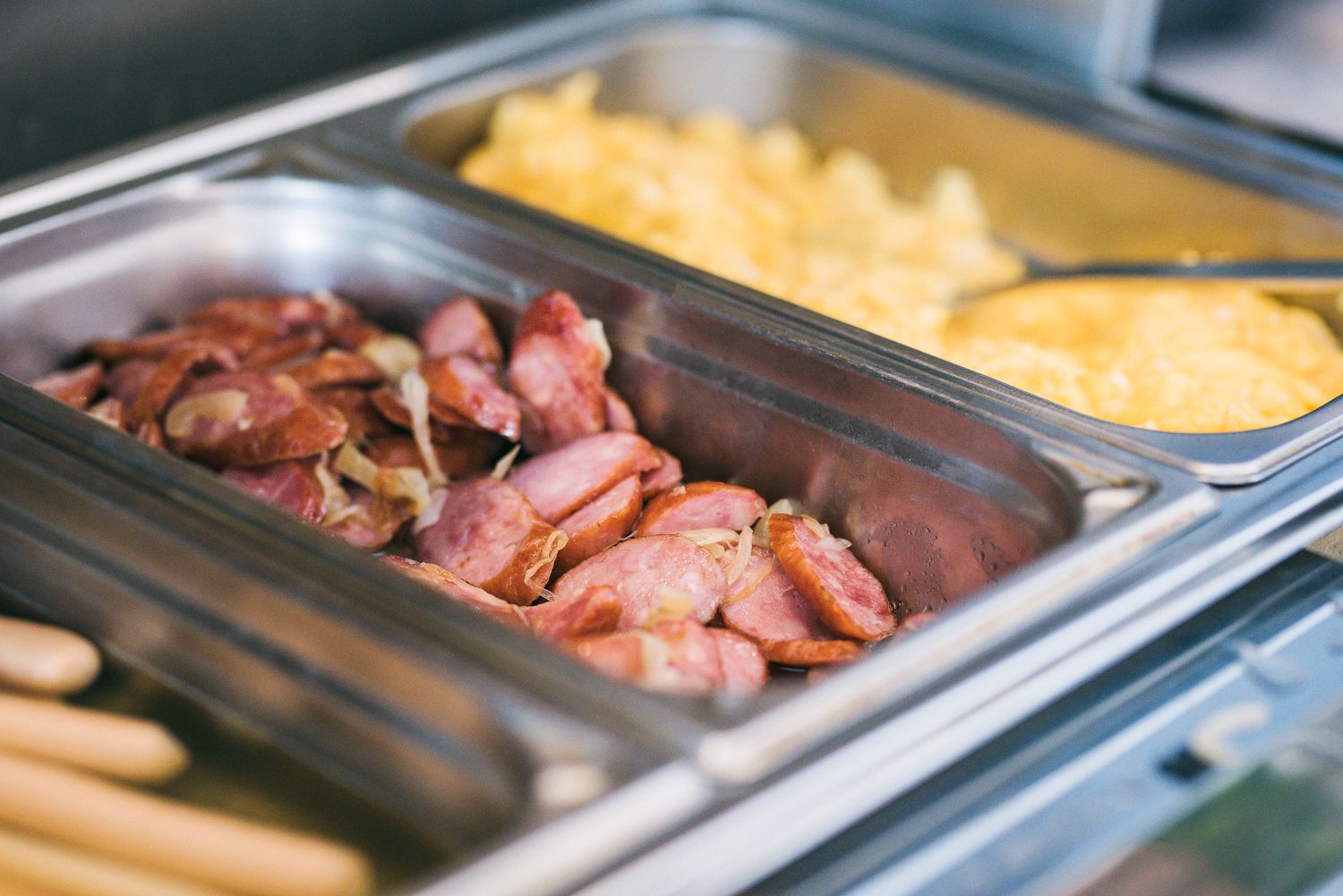 Un bufé con diversas opciones de comida, incluyendo carnes cortadas y macarrones.