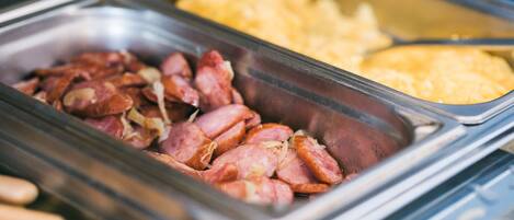 A buffet with various food options including sliced meats and macaroni.