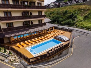 A hotel with a swimming pool, multiple balconies, and a hillside view. - Ganz & SPA (Bukovel)