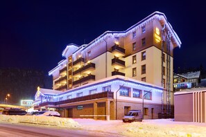 A multi-story hotel with balconies, a covered entrance, and a sign indicating it is a ski resort. - Ganz & SPA (Bukovel)