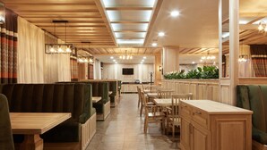 Un restaurante con paneles de madera, cabinas verdes y una barra central.