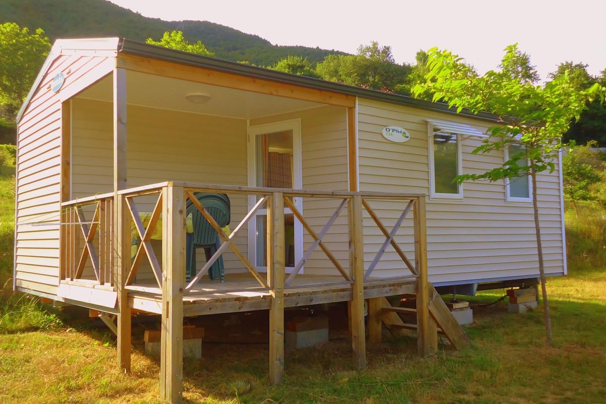 A small, single-story mobile home with a porch and a small window.