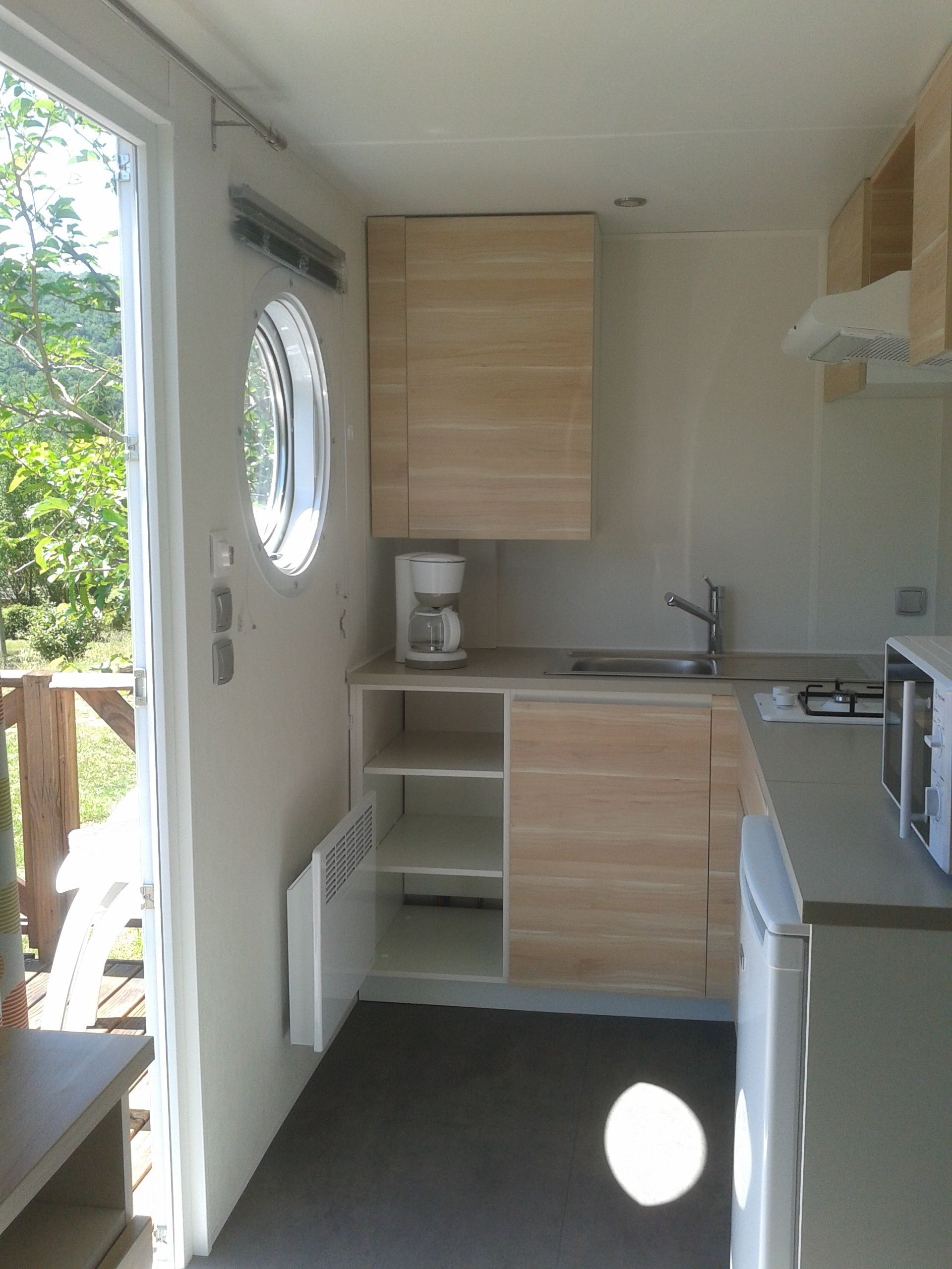 Una cocina compacta con estufa integrada, cafetera y ventana.