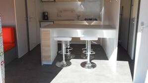 A compact kitchen with a microwave, coffee maker, and gas stove. - Camping Le Roc Qui Parle (Nant)