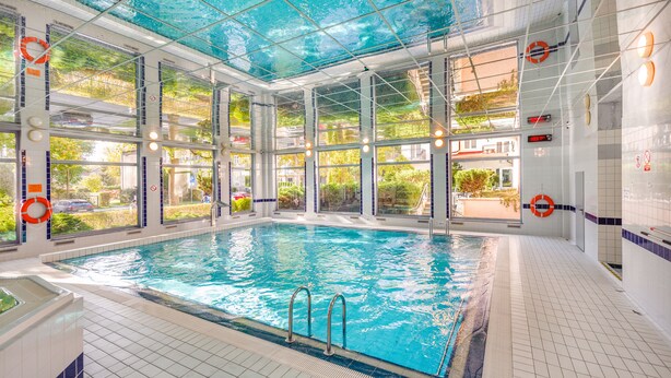 An indoor swimming pool with clear glass walls, a tiled floor, and visible windows. - Apartamenty Sun & Snow Olymp (Kolobrzeg)