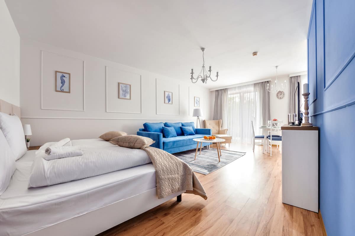 Una habitación de hotel moderna con una cama, un sofá azul, una zona de comedor y un candelabro.