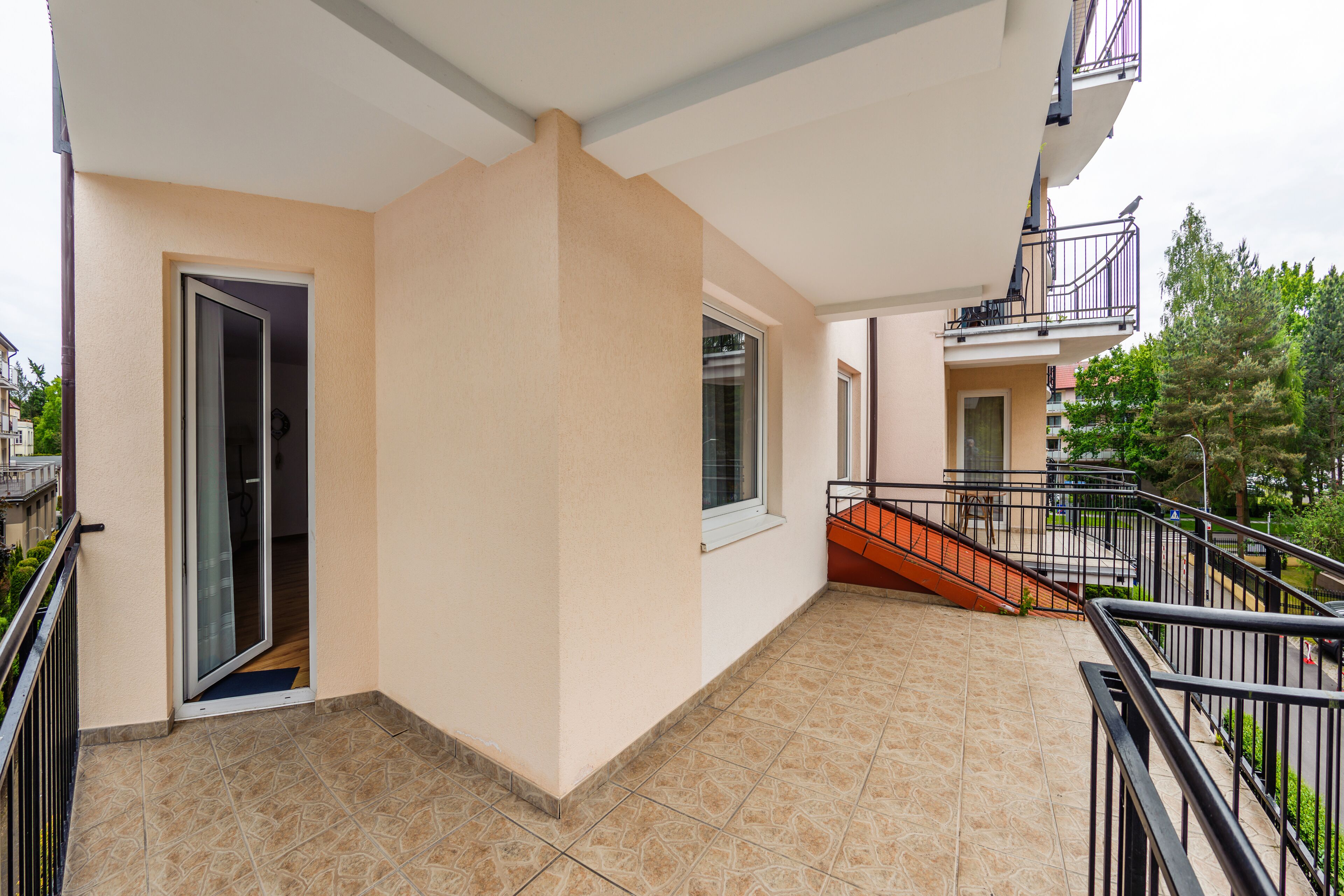 A residential balcony with a sliding glass door, a small window, and a staircase leading to an upper floor.