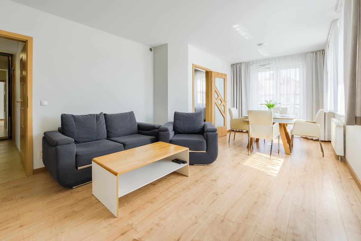Una sala de estar moderna con un sofá gris, una mesa de centro de madera y un comedor con una mesa y sillas.