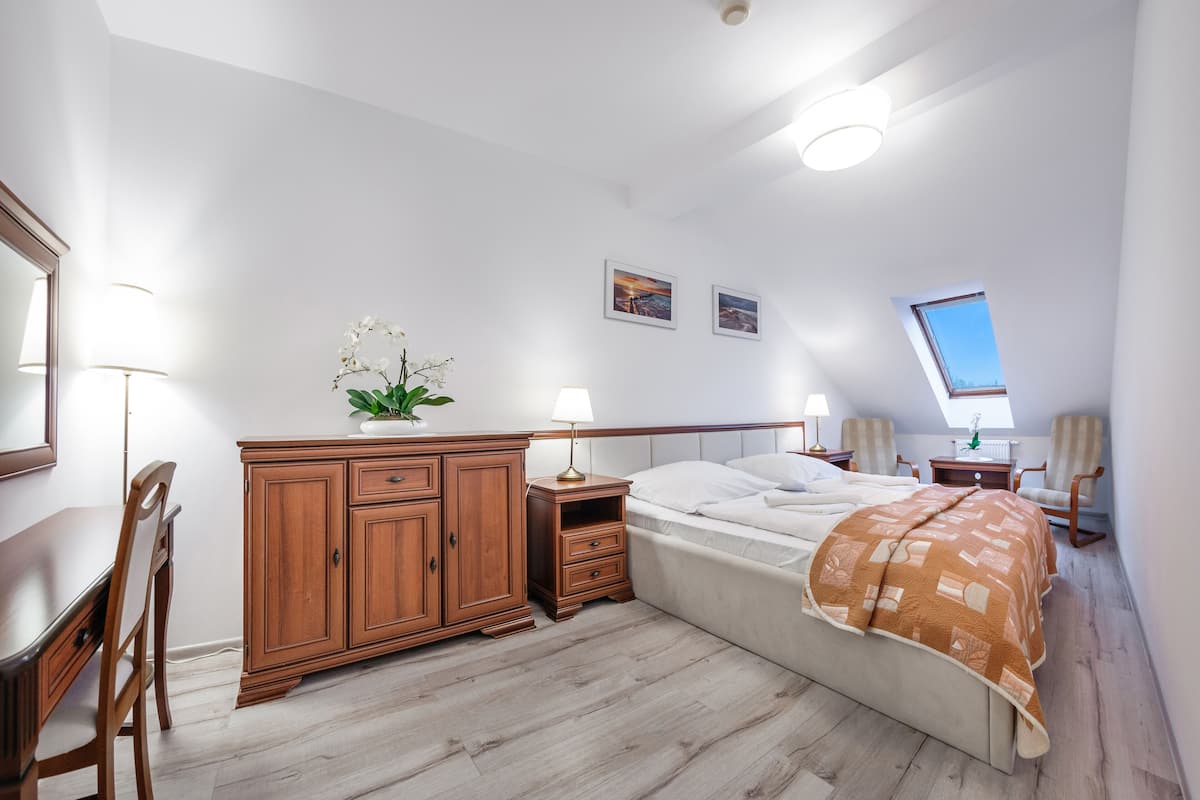 Un dormitorio con cama, cómoda de madera, escritorio y sillas.