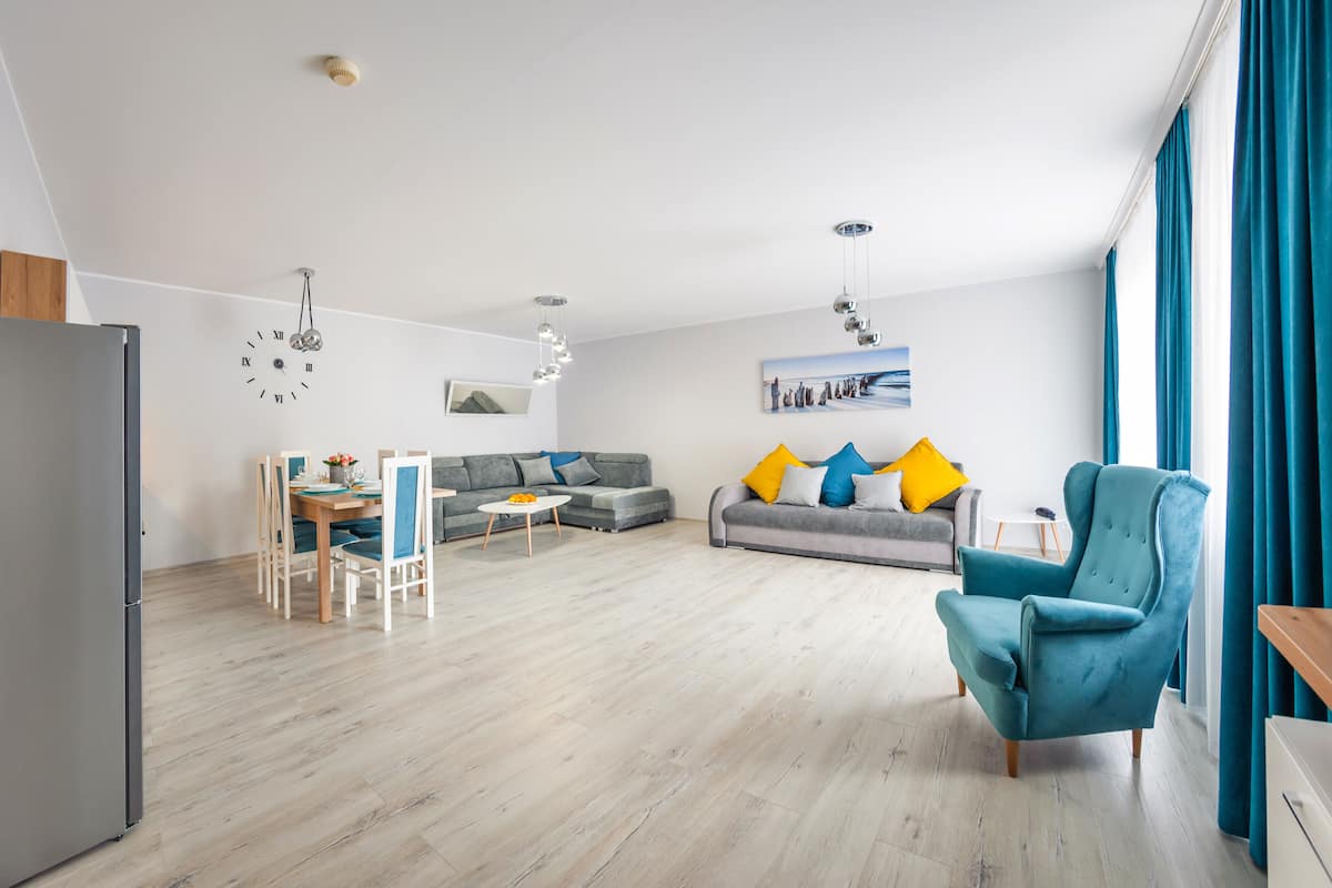 Amplia sala de estar con mesa de comedor, sofás y un ventanal con cortinas.