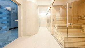 A modern hotel corridor with a glass door on the left, a wooden sauna area on the right, and a tiled floor. - Apartamenty Sun & Snow Olymp (Kolobrzeg)