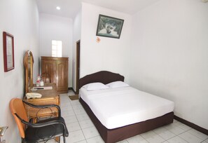 A bedroom with a bed, a wooden wardrobe, a chair, and a desk with a mirror.