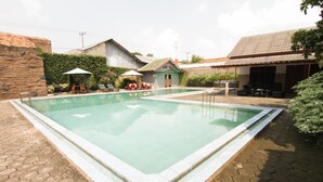 A rectangular swimming pool with a tiled edge, surrounded by a paved area with hexagonal tiles. - Grand Ciwareng Inn (Purwakarta)