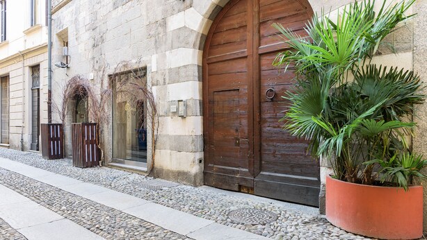 Um edifício de pedra com uma grande porta de madeira, um vaso de planta e um caminho de pedras.