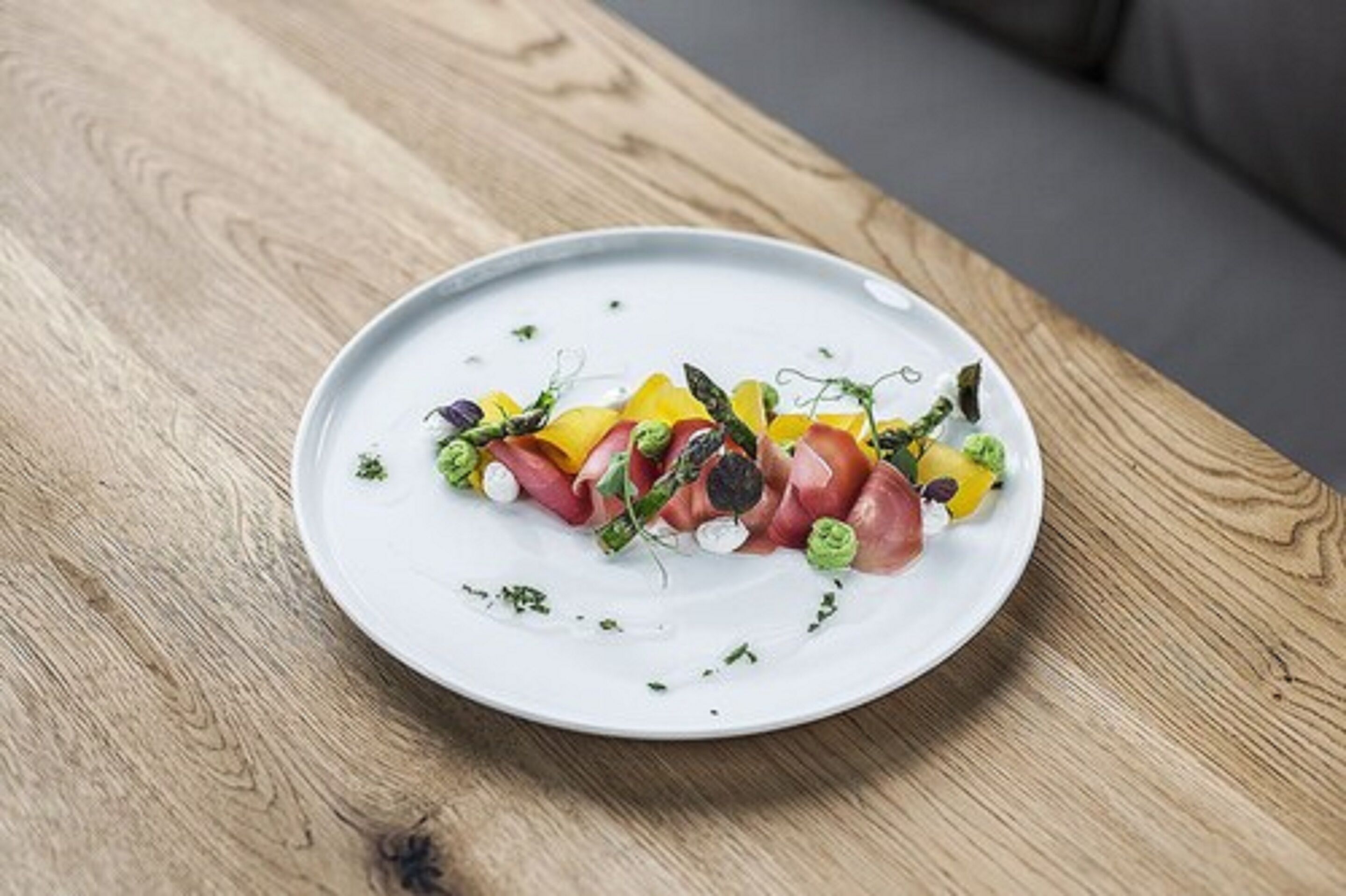A white plate with a colorful arrangement of food on a wooden table.