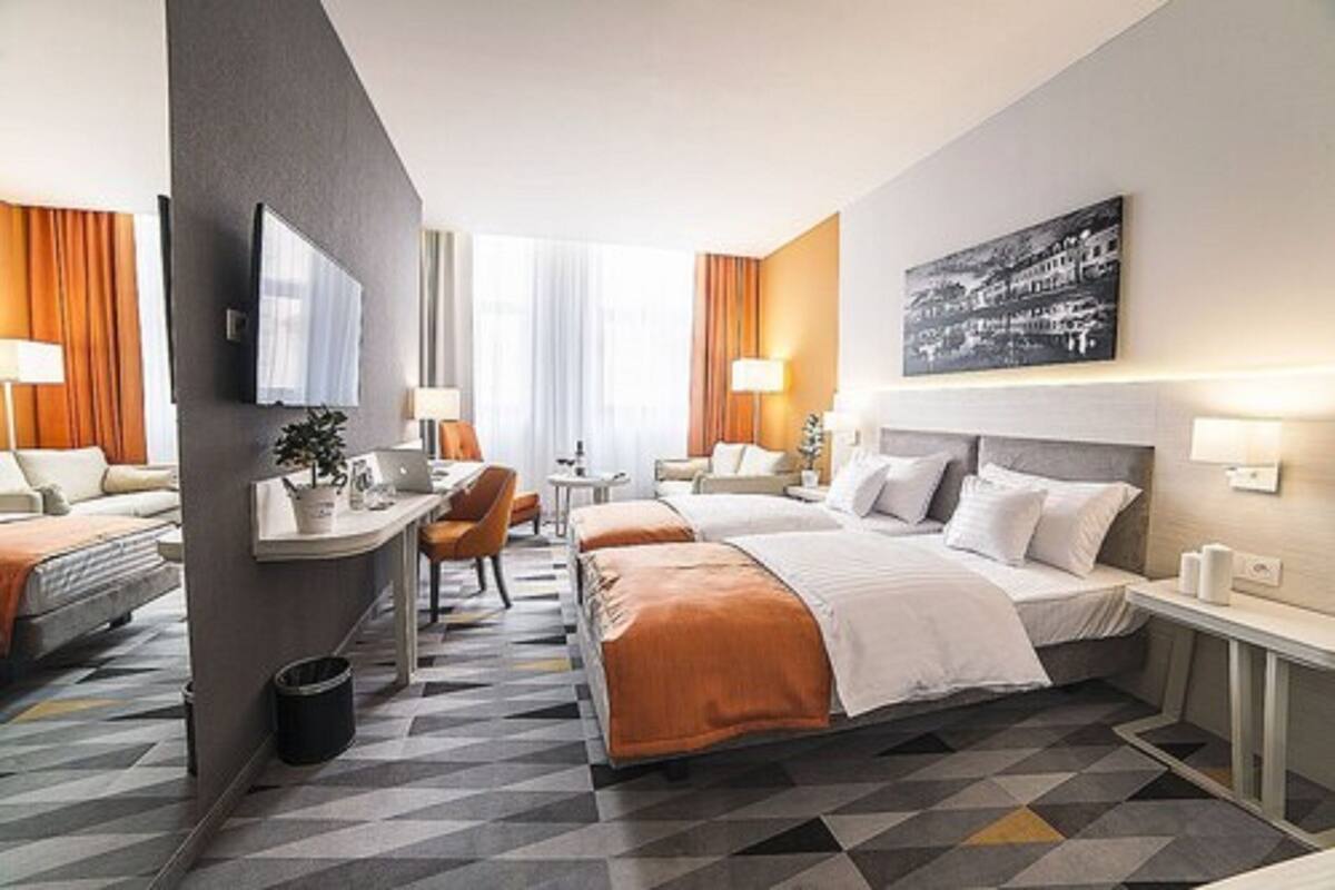 A hotel room with a large bed, a desk, a chair, and a TV.