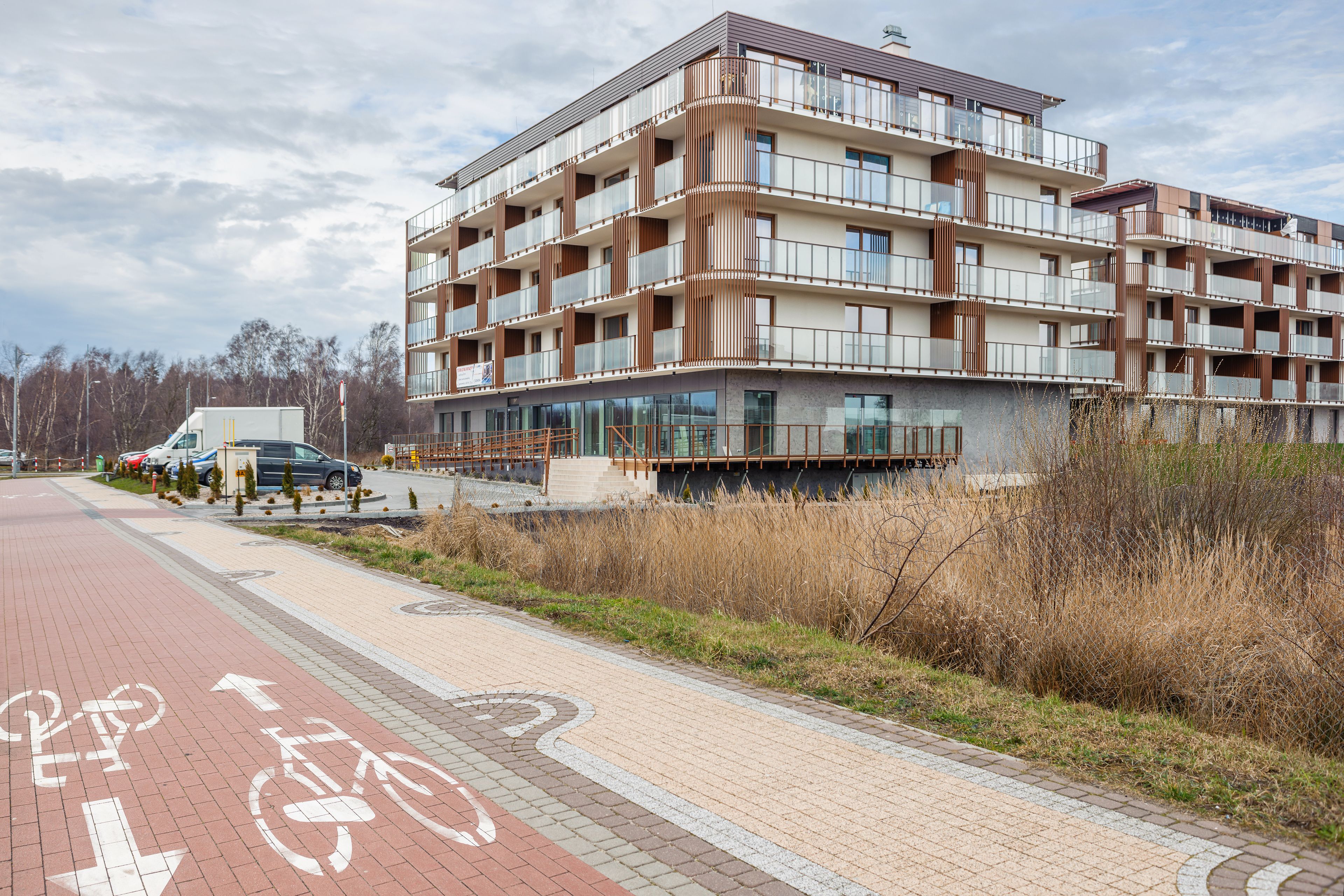 Un immeuble résidentiel à plusieurs étages doté de balcons, d’une piste cyclable et d’un espace de stationnement.