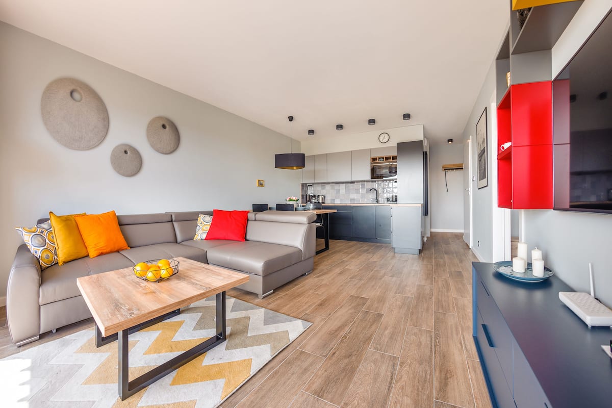 Ein modernes Wohnzimmer mit einer Couch, einem Couchtisch und einer Küche im Hintergrund.