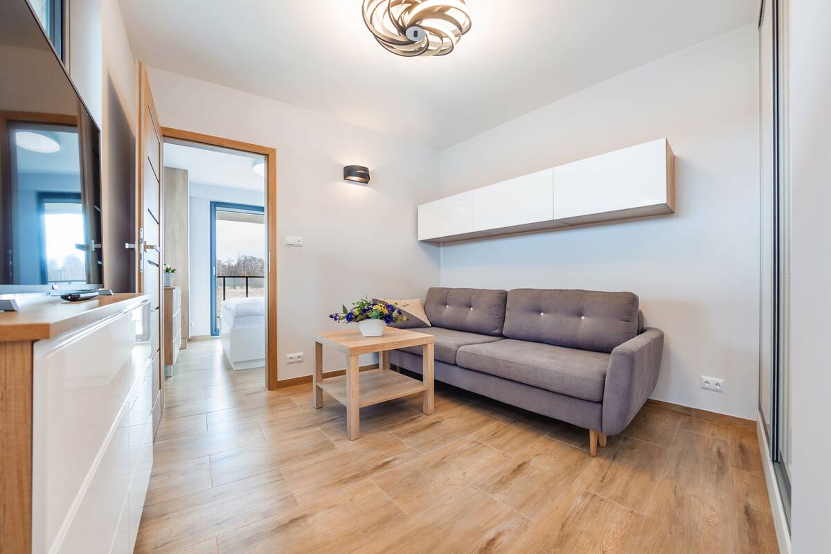 Ein modernes Wohnzimmer mit grauem Sofa, einem Holztisch und einem integrierten Fernseher.