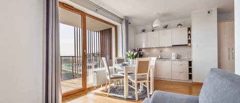 A modern apartment with a dining area, kitchen, and a balcony with a view.