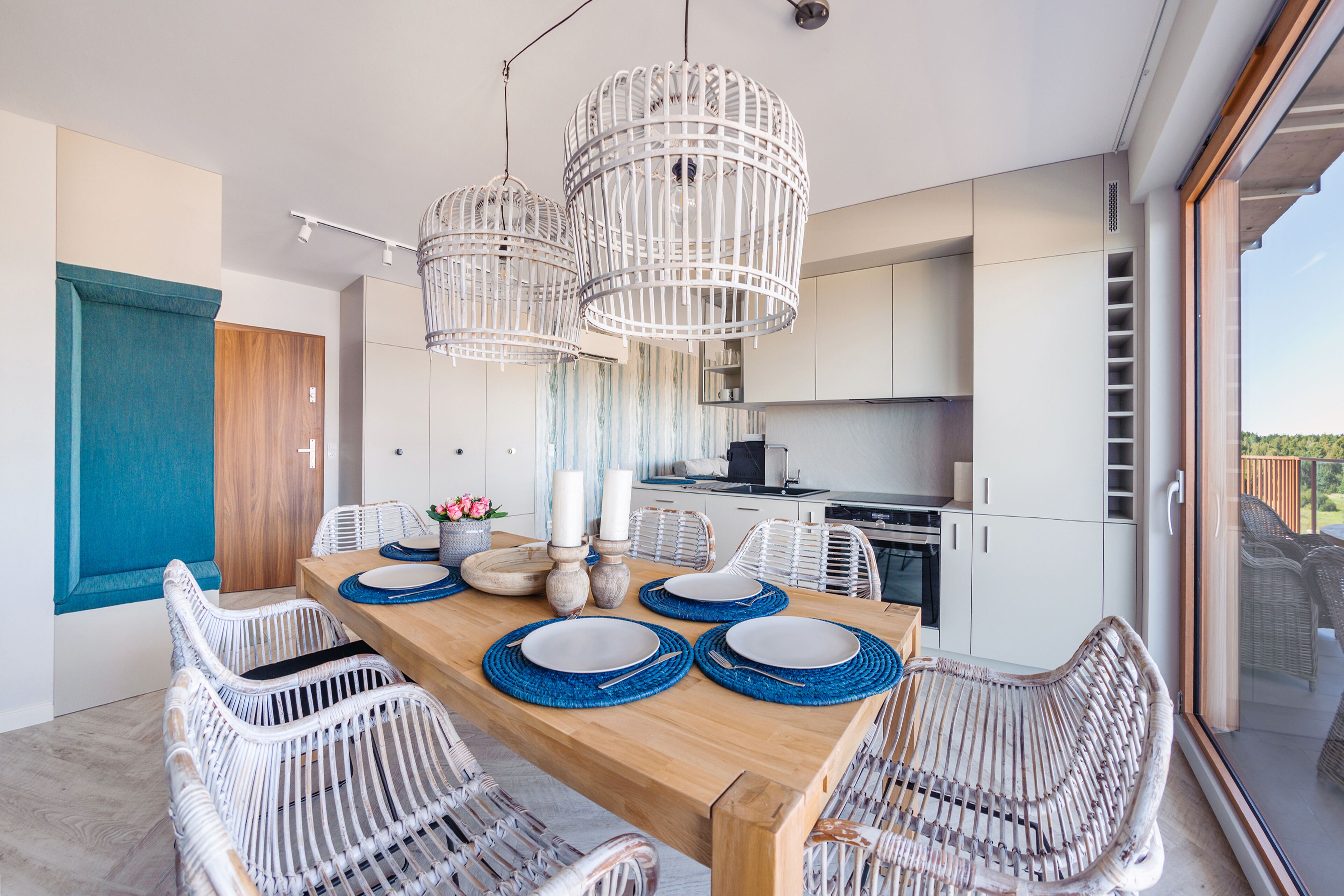 Ein moderner Essbereich mit einem Holztisch, weißen Korbstühlen und blauen Platzsets.