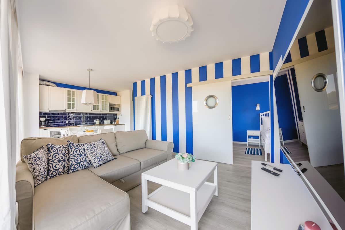 Ein modernes Wohnzimmer mit einer Couch, einem Couchtisch und einer Küche im Hintergrund.