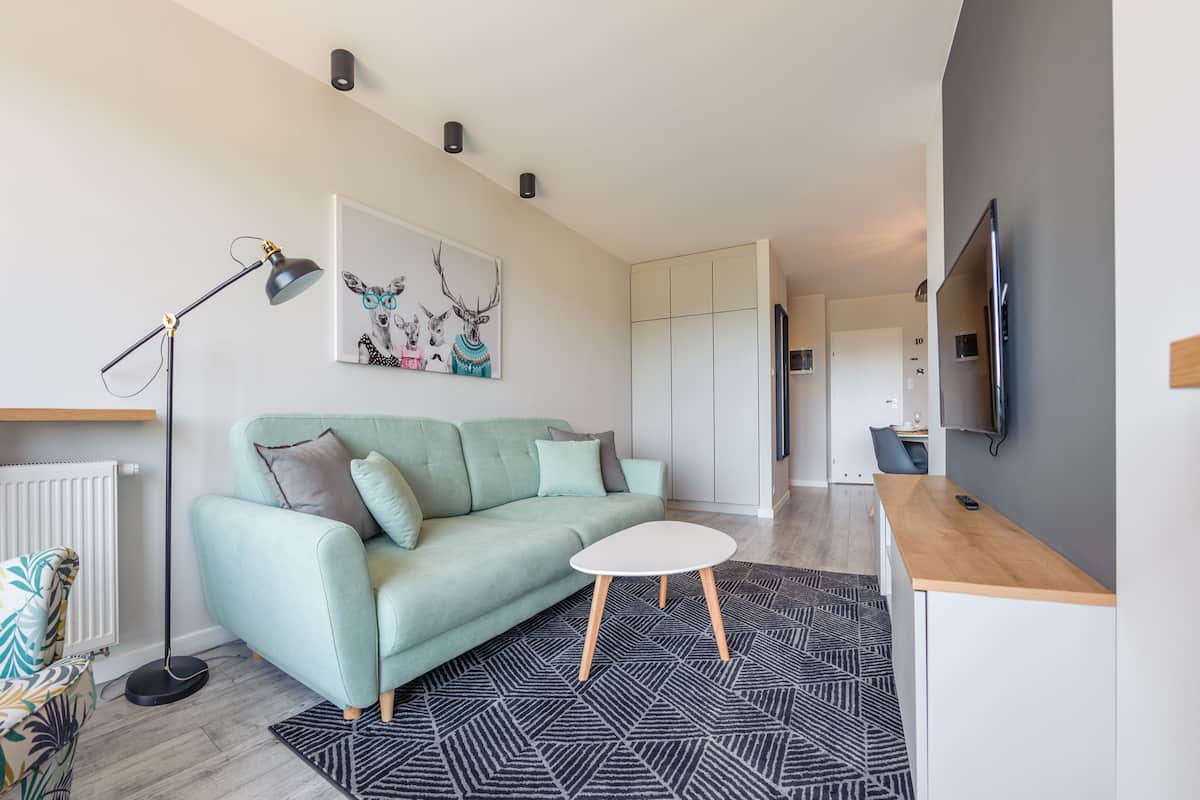 Ein modernes Wohnzimmer mit einem hellgrünen Sofa, einem weißen Couchtisch und einem schwarz-weißen Teppich.