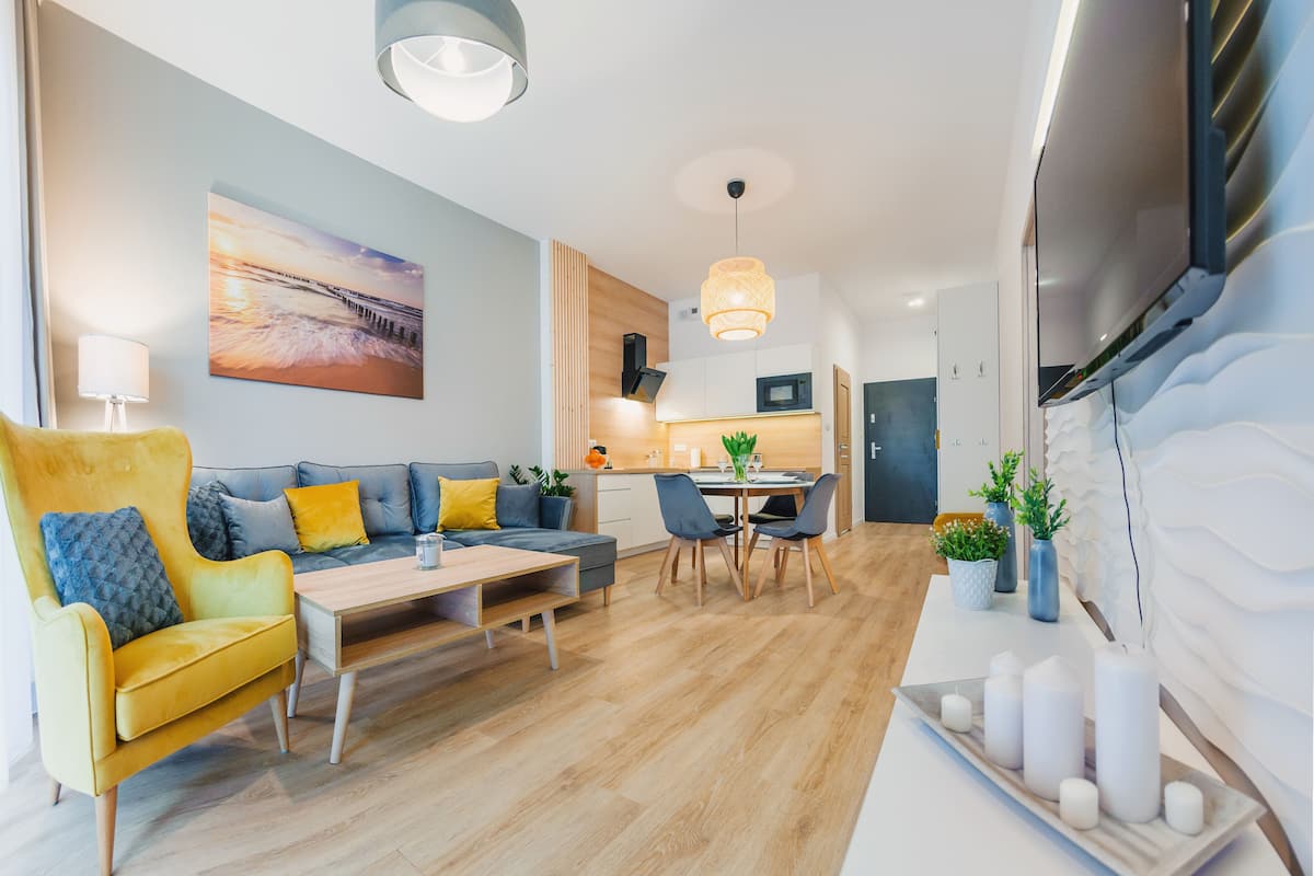 A modern living room with a sofa, coffee table, and dining area.