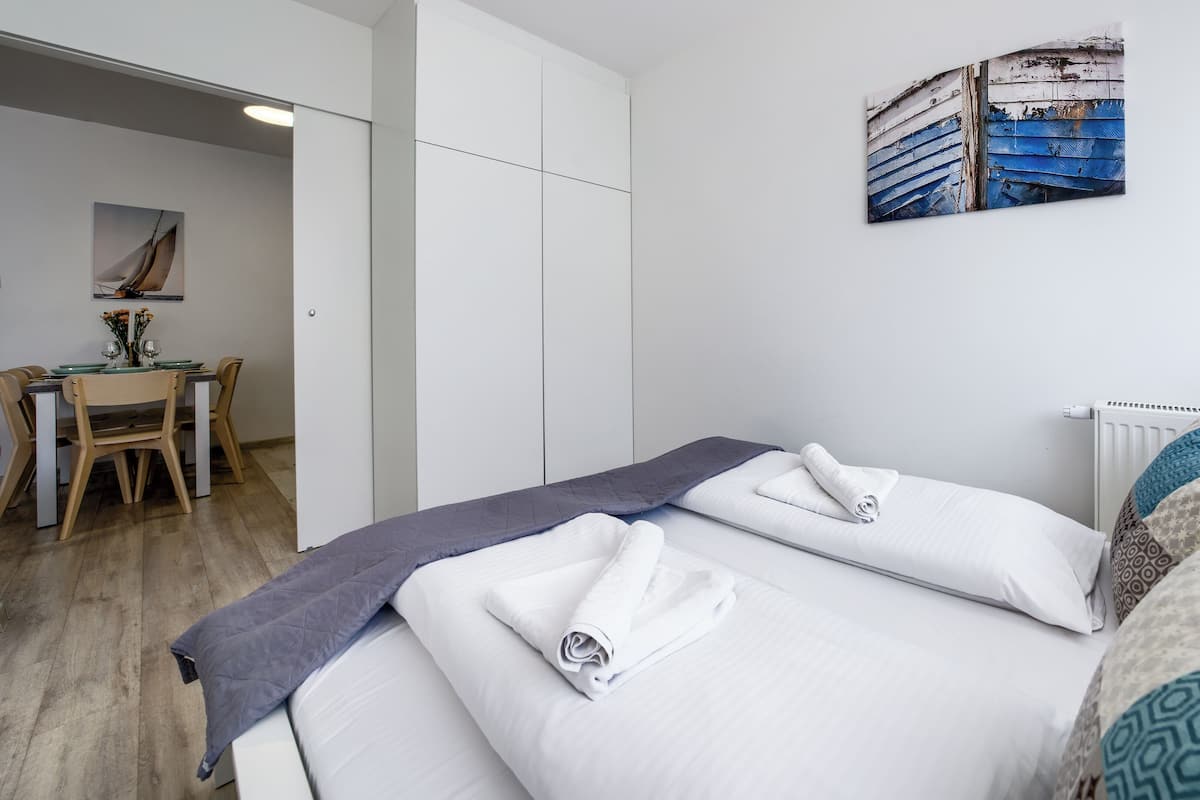 A hotel room with two beds, a dining table with chairs, and a painting on the wall.