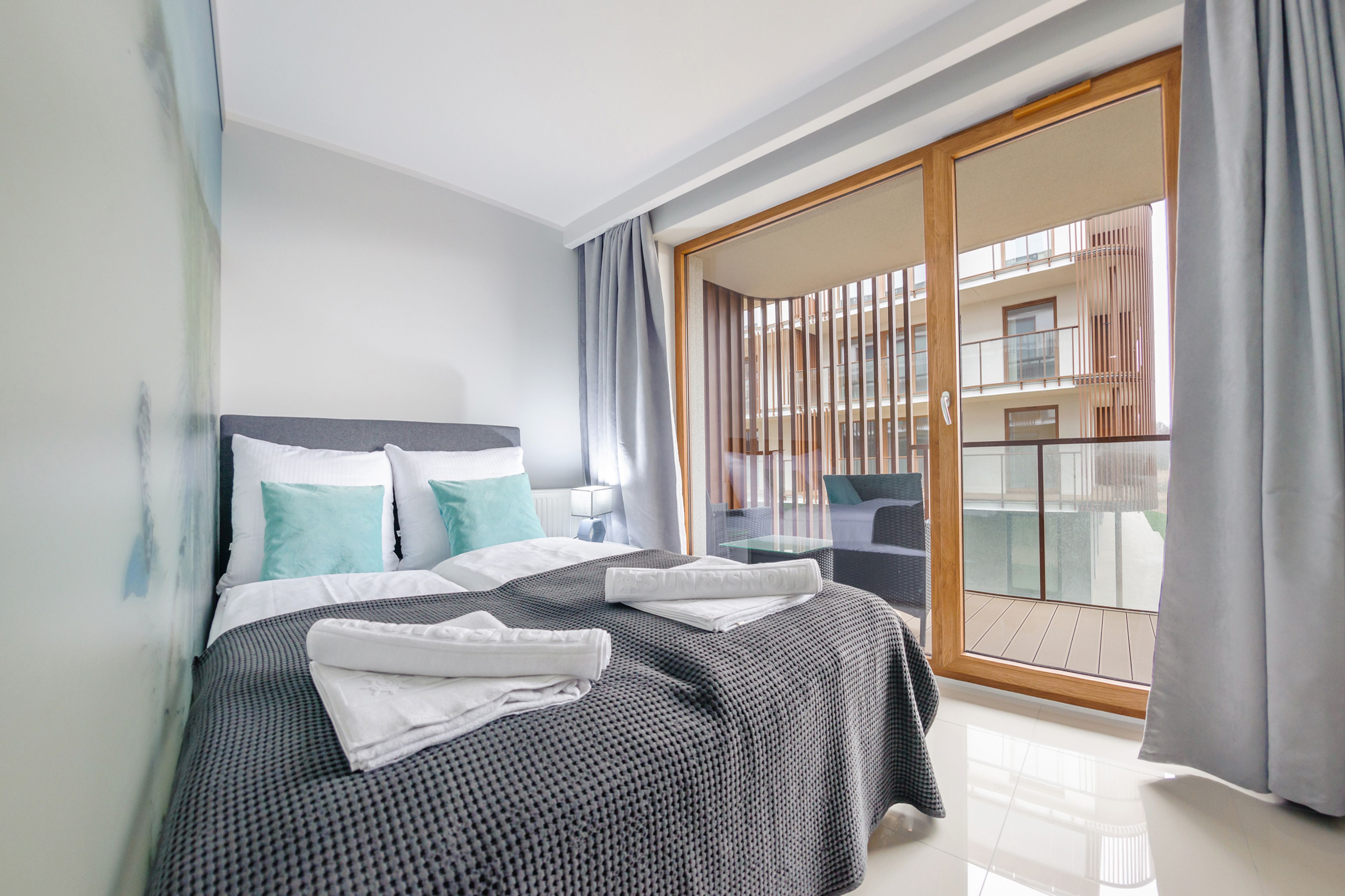 Habitación de hotel moderna con una cama grande, un balcón con vistas y una puerta corrediza de vidrio.
