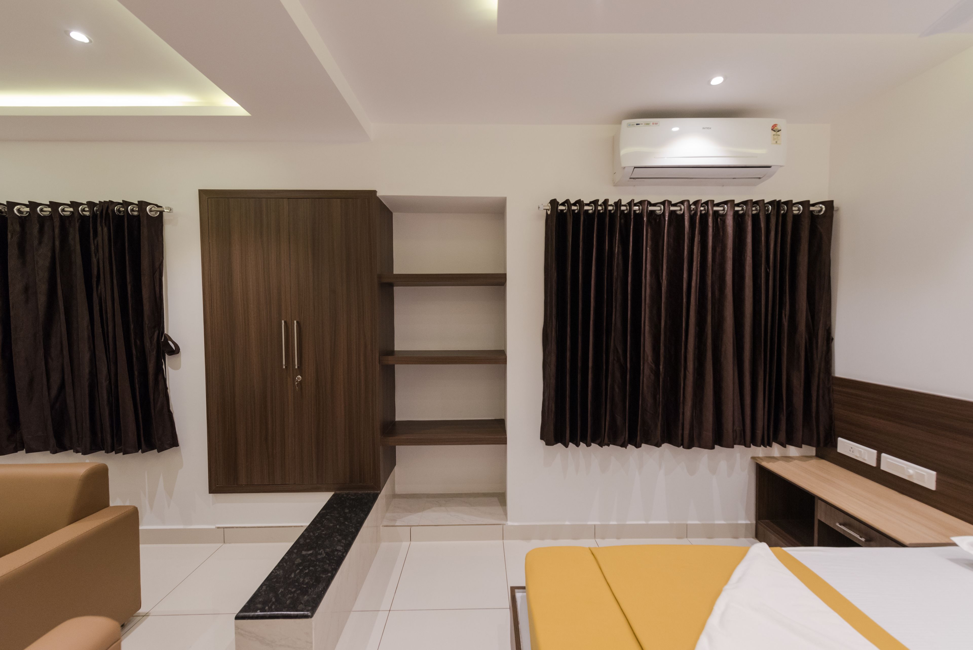 Una habitación de hotel moderna con cama, escritorio, armario y unidad de aire acondicionado.