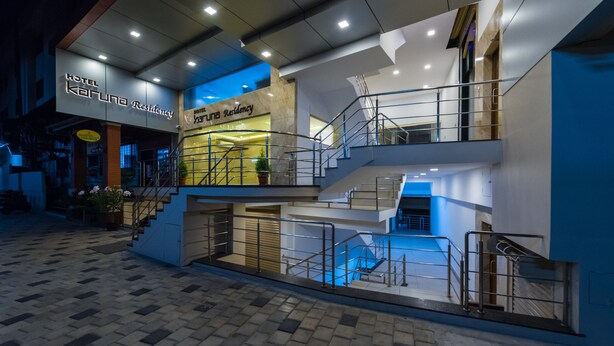A modern hotel with a prominent entrance, multiple floors, and a visible staircase. - Hotel Karuna Residency (Mangaluru)