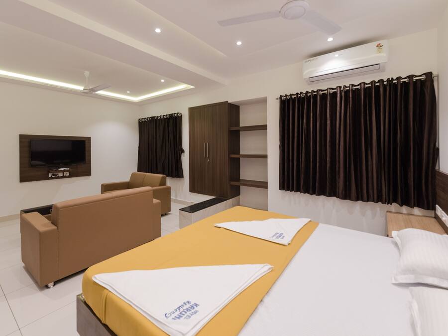 Una habitación de hotel con cama, sofá, televisor, ventilador de techo y aire acondicionado.