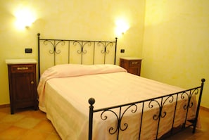Un dormitorio con cama, dos mesitas de noche e iluminación en la pared.