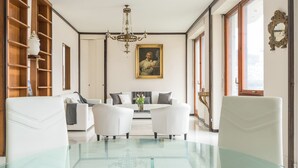 Ein modernes Wohnzimmer mit einem Glastisch, weißen Sofas und einer Chandelüster.