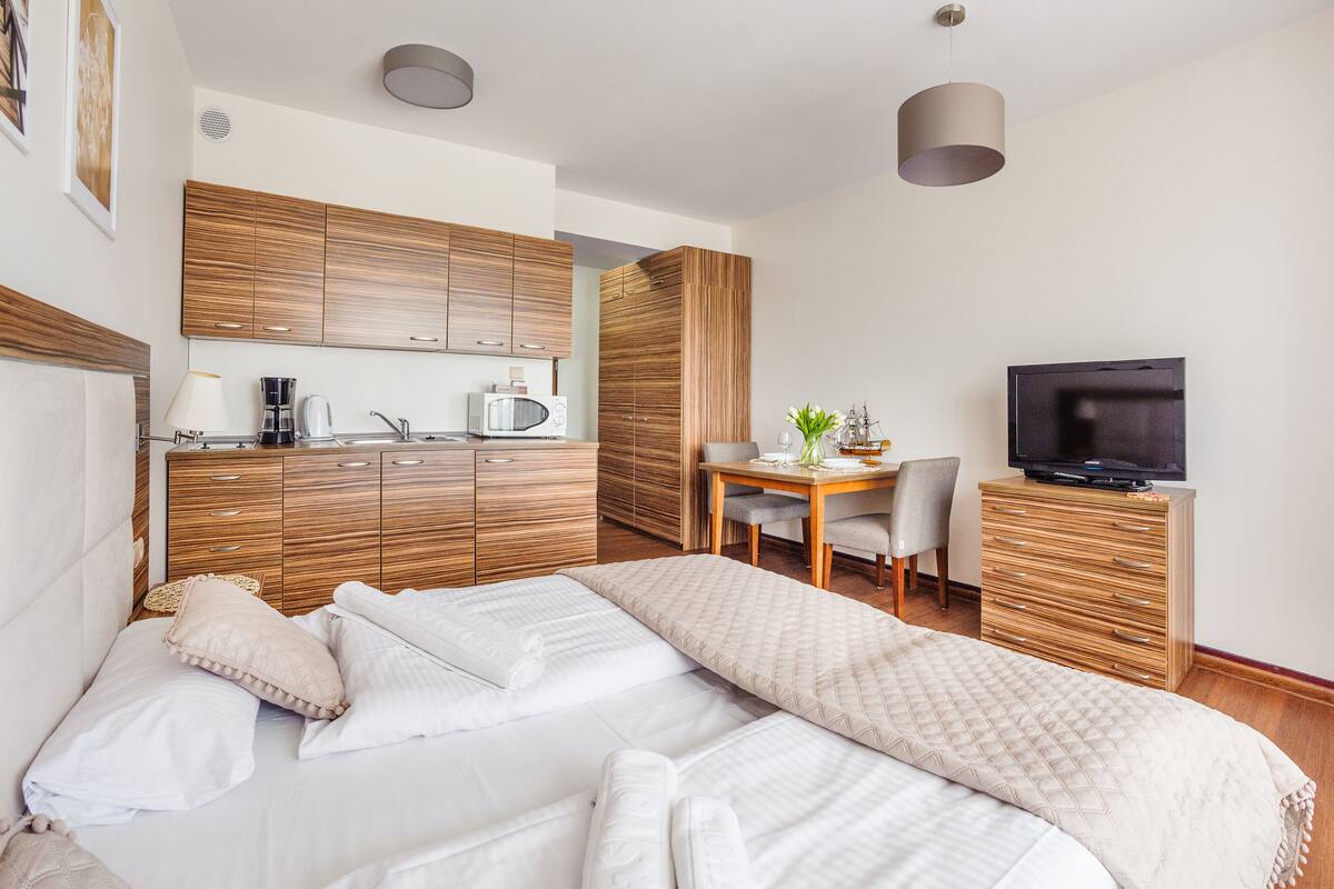 Een hotelkamer met een bed, een bureau, een televisie en een kitchenette.