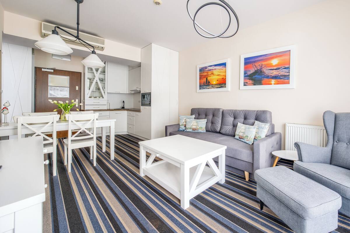 Een moderne woonkamer met een bank, fauteuil en een eethoek met een tafel en stoelen.