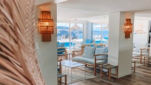 A modern lounge area with a view of the sea, featuring wooden furniture and a glass partition.