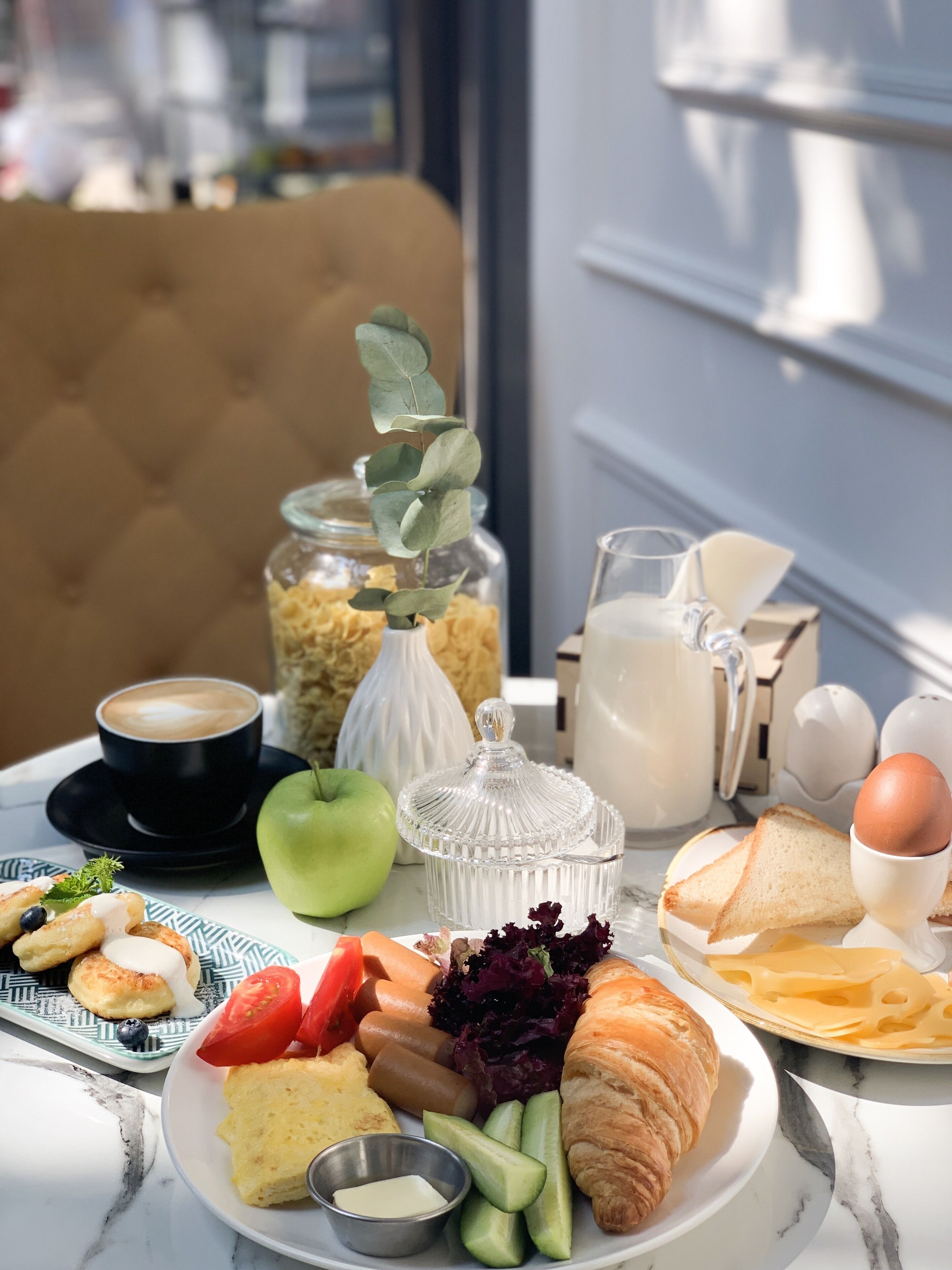 Ein Frühstückstisch mit verschiedenen Speisen, darunter Brot, Eier und Gemüse, auf einer Marmortafel.
