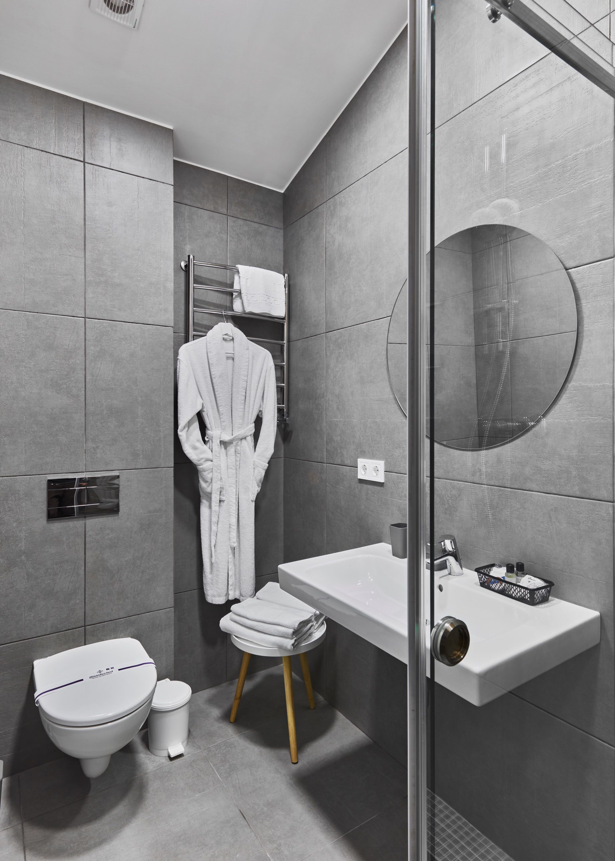 A modern bathroom with a toilet, sink, and a round mirror.