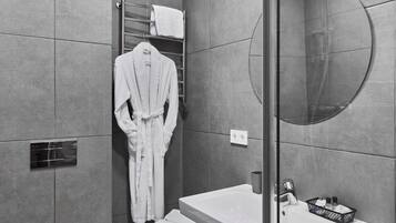 A modern bathroom with a toilet, sink, and a round mirror.
